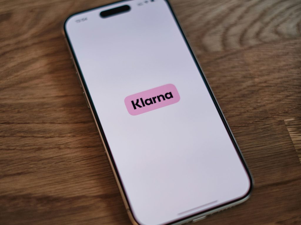 Klarna logo on a mobile smartphone app as the company aims to address the lack of interoperability between conversational AI agents and backend payment systems by backing Google’s Universal Commerce Protocol (UCP), an open standard designed to unify how AI agents discover products and execute transactions.